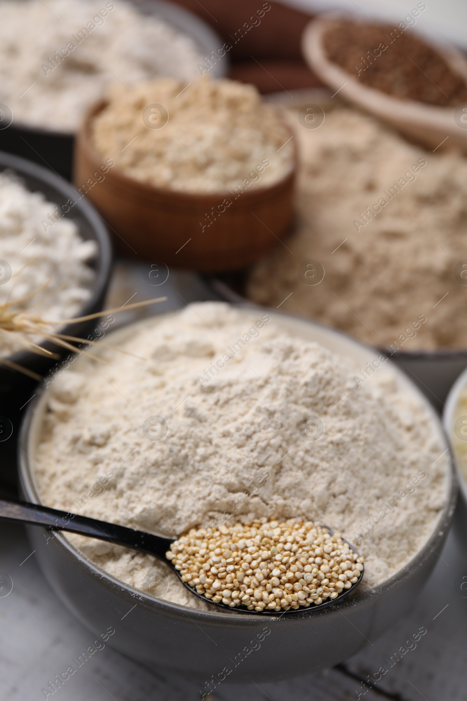 Photo of Bowls with different types of flour and ingredients on white wooden table, closeup