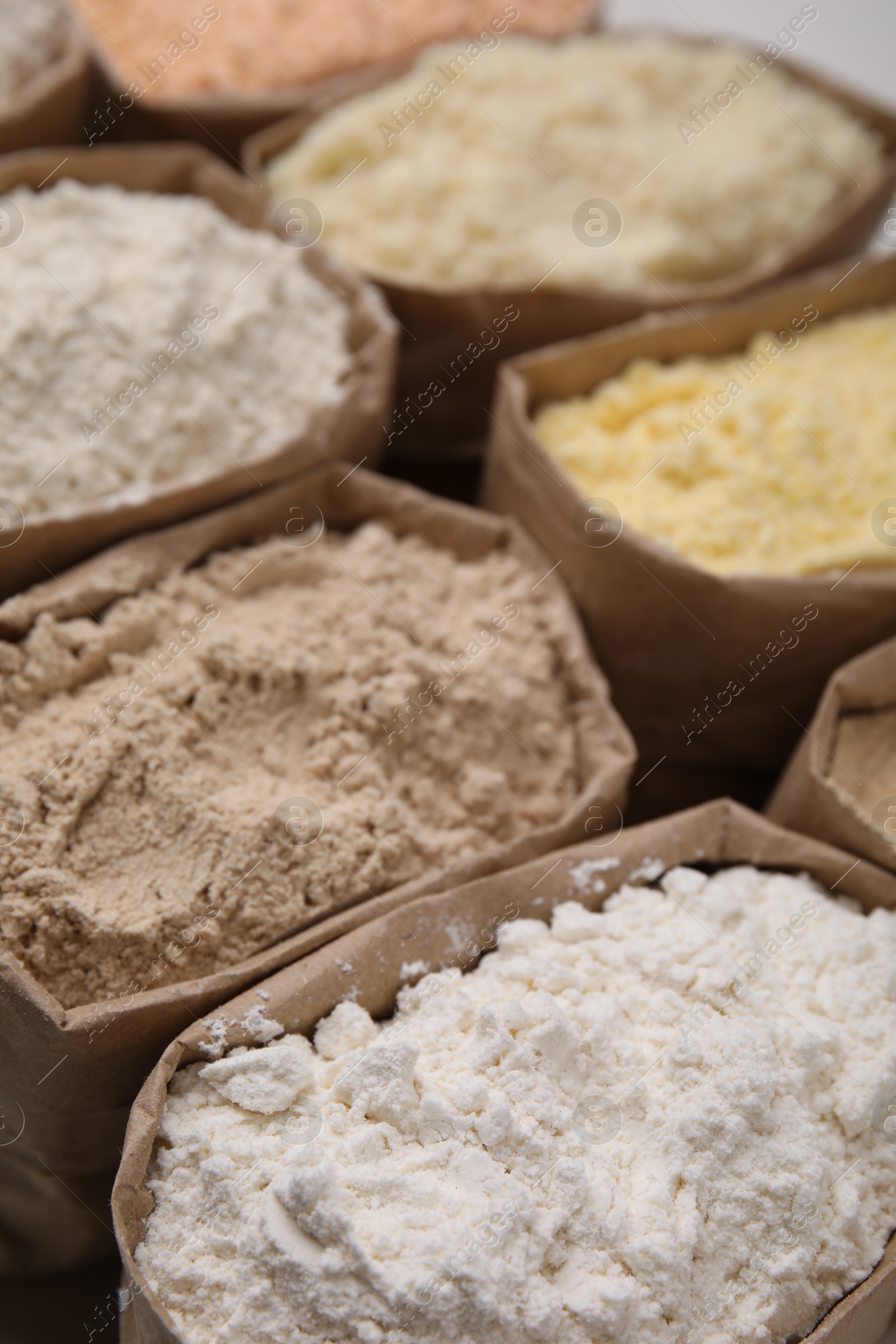 Photo of Paper sacks with different types of flour as background, closeup