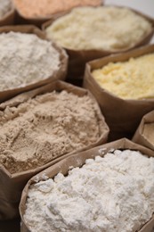 Photo of Paper sacks with different types of flour as background, closeup