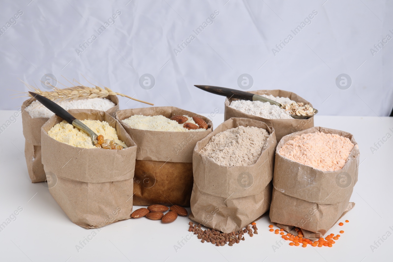 Photo of Paper bags with different types of flour on white background