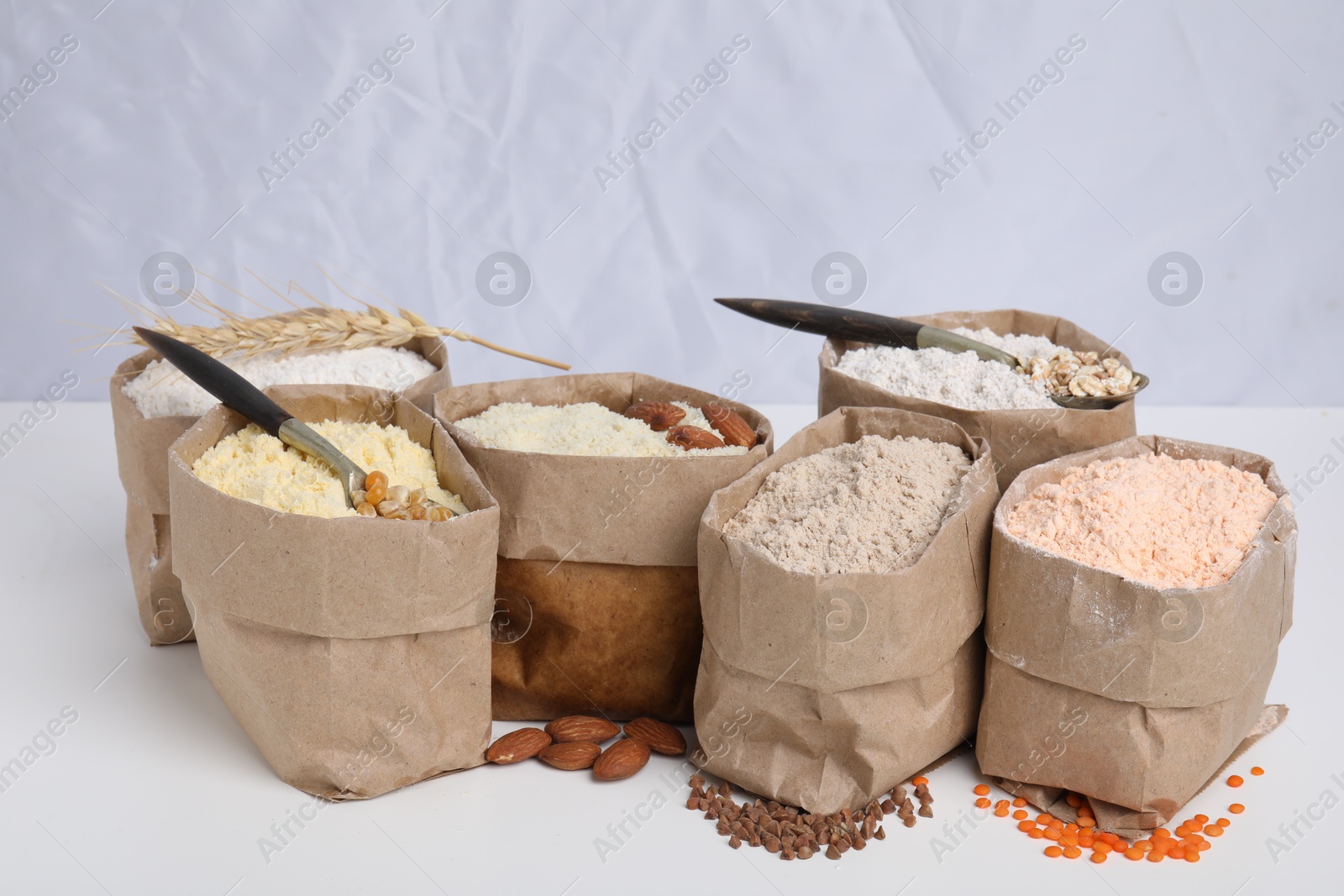 Photo of Paper bags with different types of flour on white background