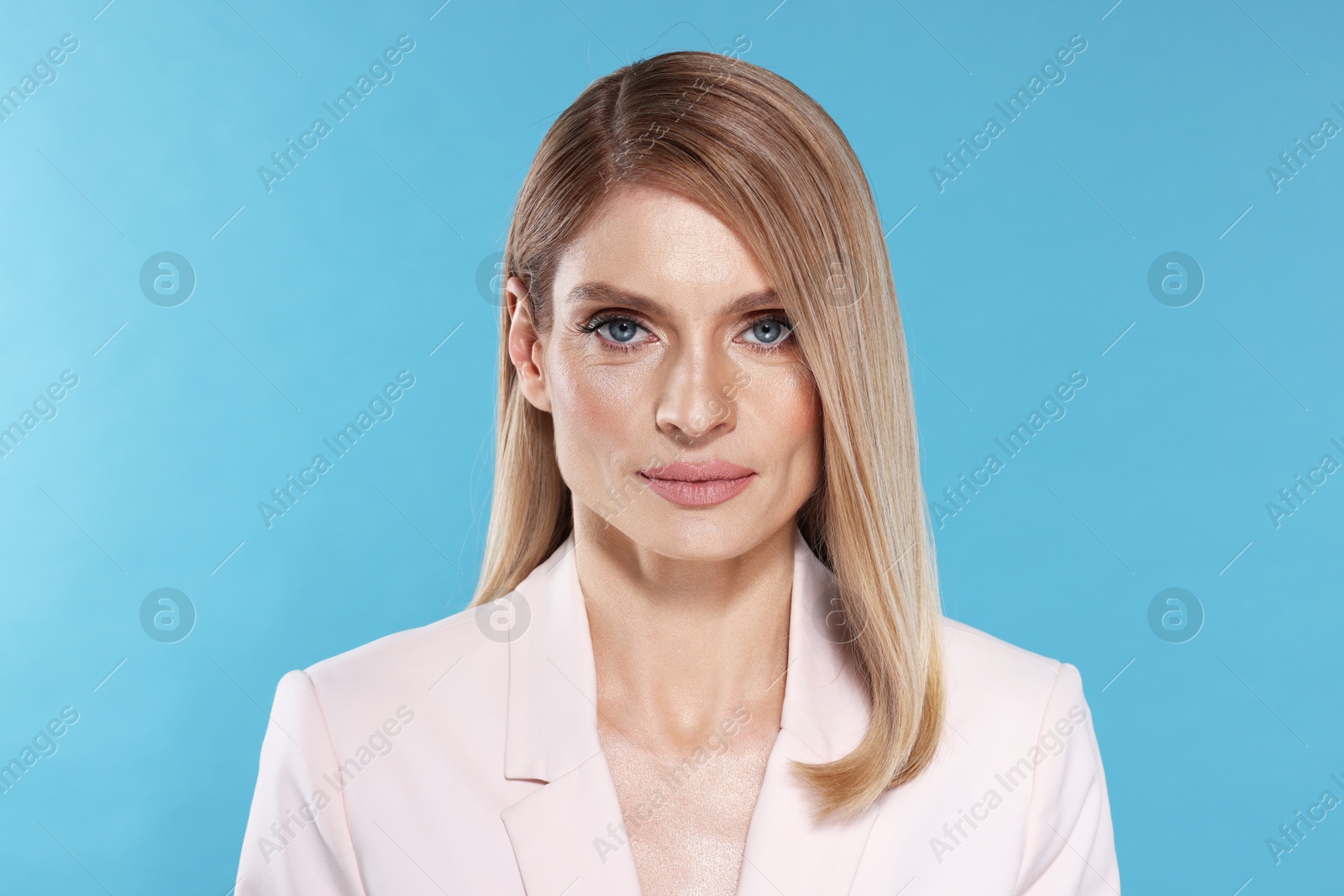 Photo of Portrait of beautiful woman with straight blonde hair on light blue background