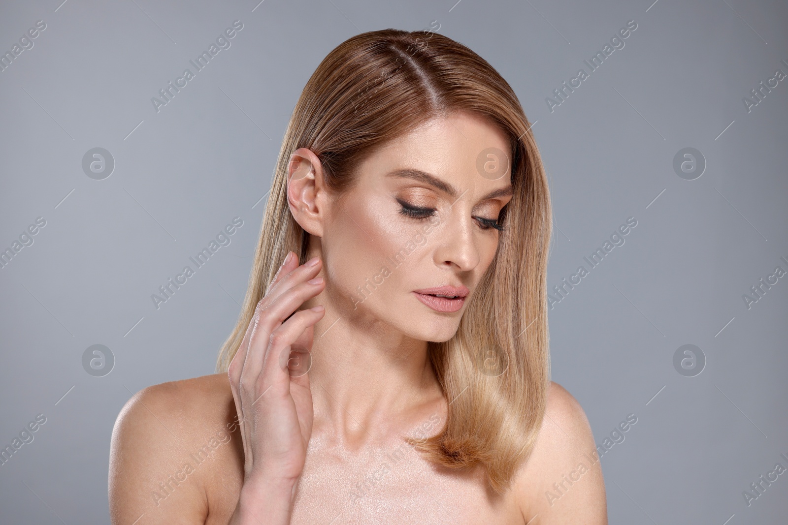 Photo of Portrait of beautiful woman with straight blonde hair and stylish makeup on grey background