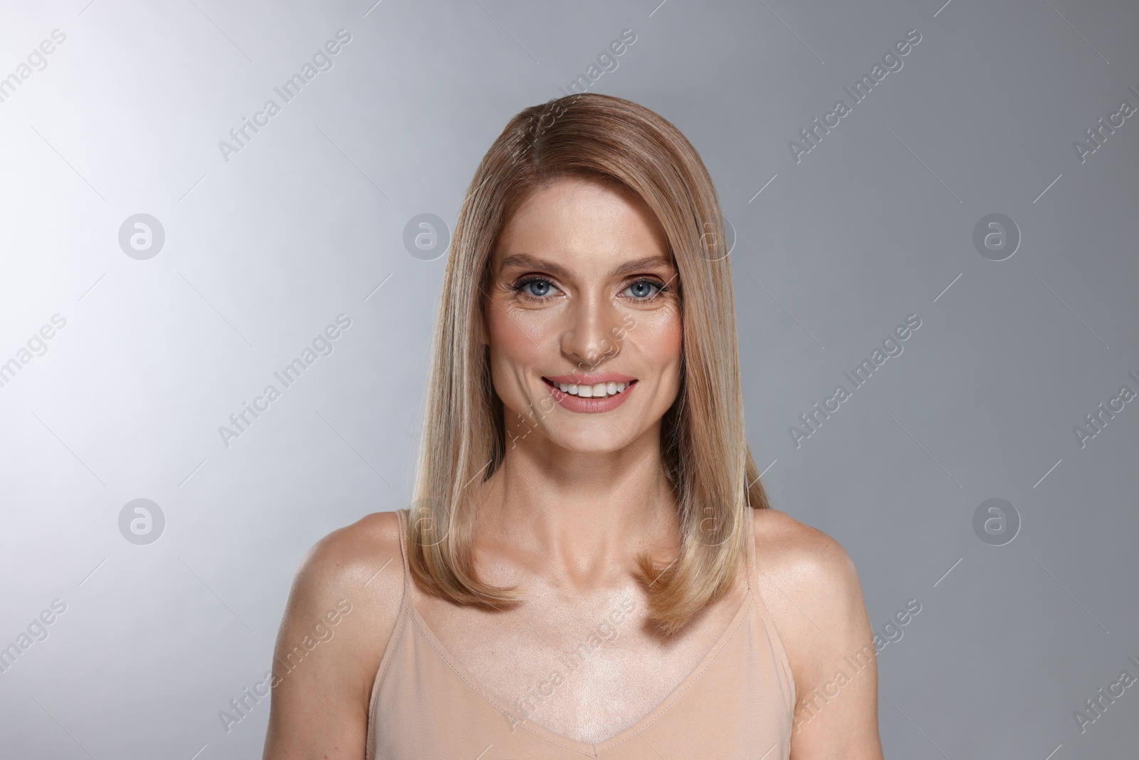 Photo of Portrait of beautiful happy woman with straight blonde hair on light grey background