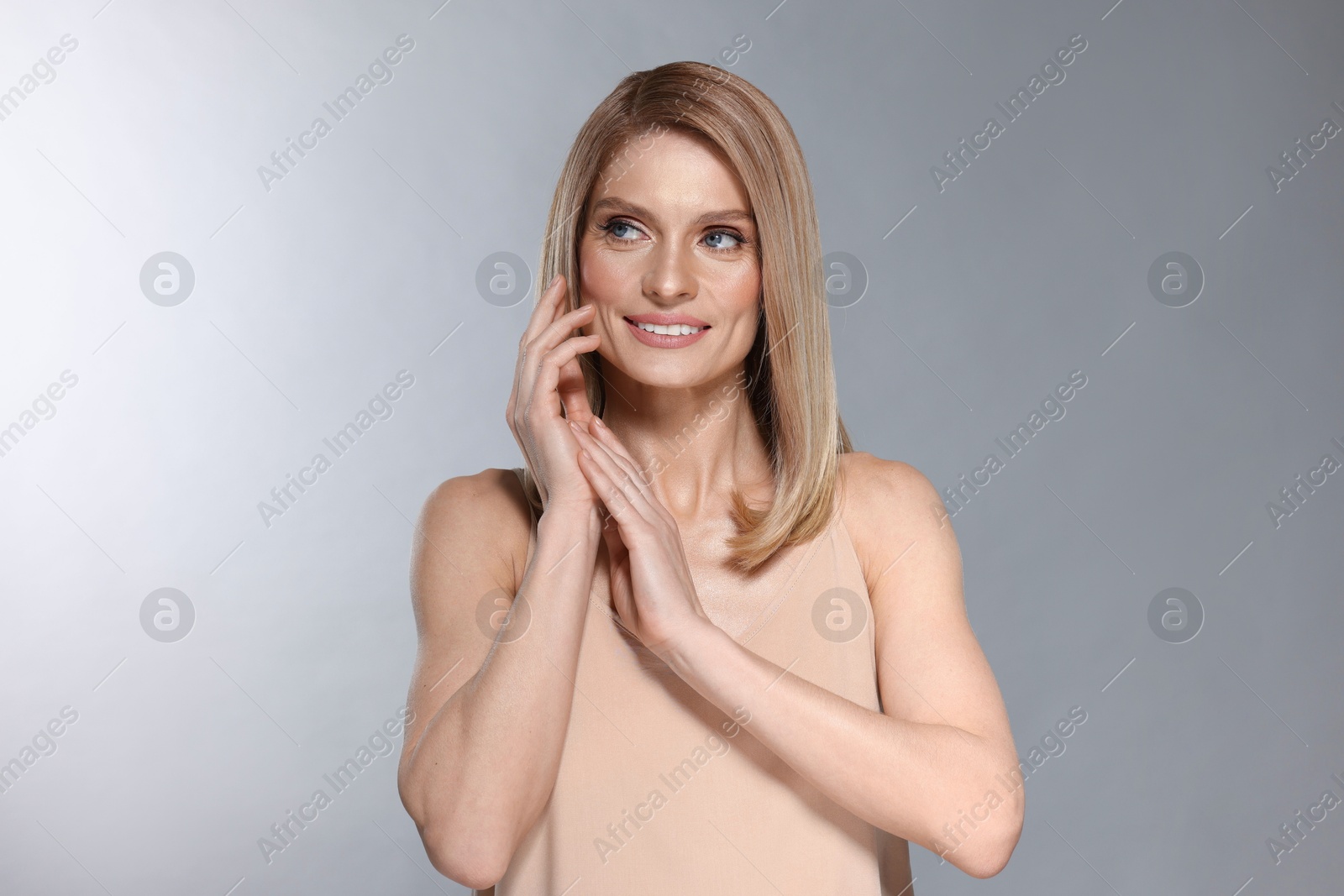 Photo of Portrait of beautiful happy woman with straight blonde hair on light grey background