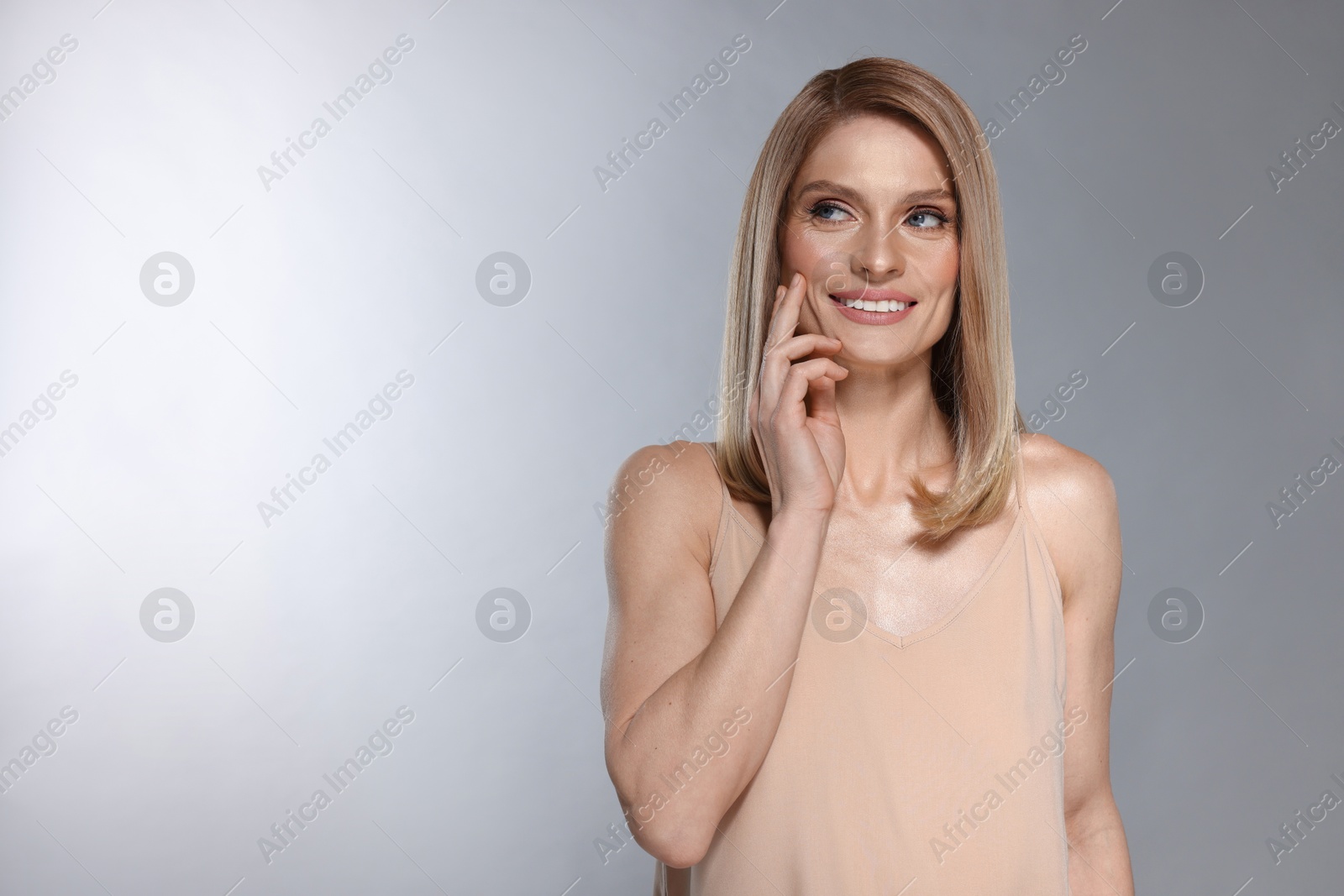 Photo of Beautiful happy woman with straight blonde hair on light grey background, space for text