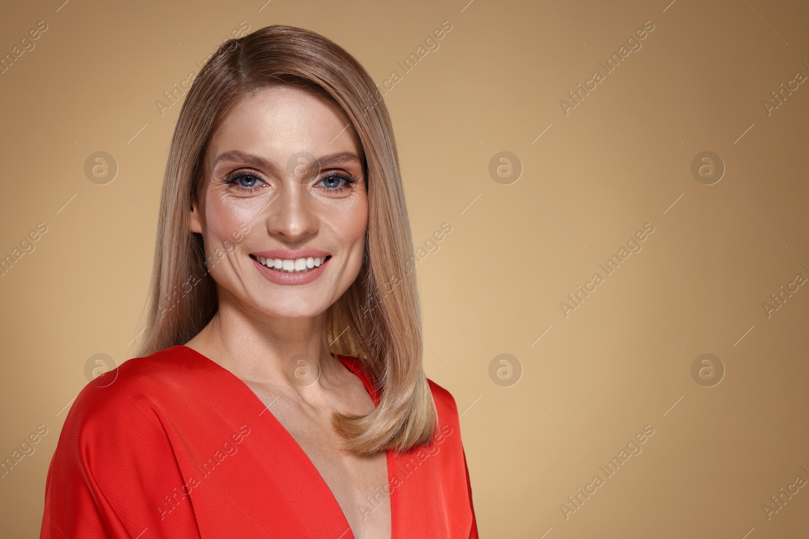 Photo of Portrait of beautiful happy woman with straight blonde hair on beige background, space for text