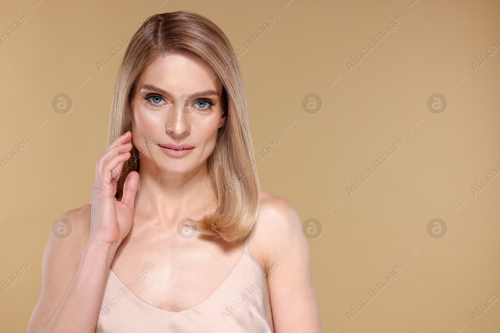 Photo of Portrait of beautiful woman with straight blonde hair on beige background, space for text