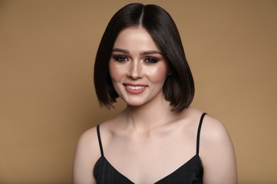 Photo of Portrait of beautiful happy young woman with gorgeous straight hair on dark beige background