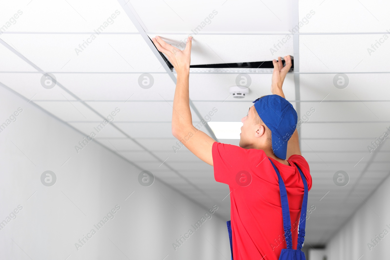 Photo of Suspended ceiling installation. Builder working with PVC tile indoors