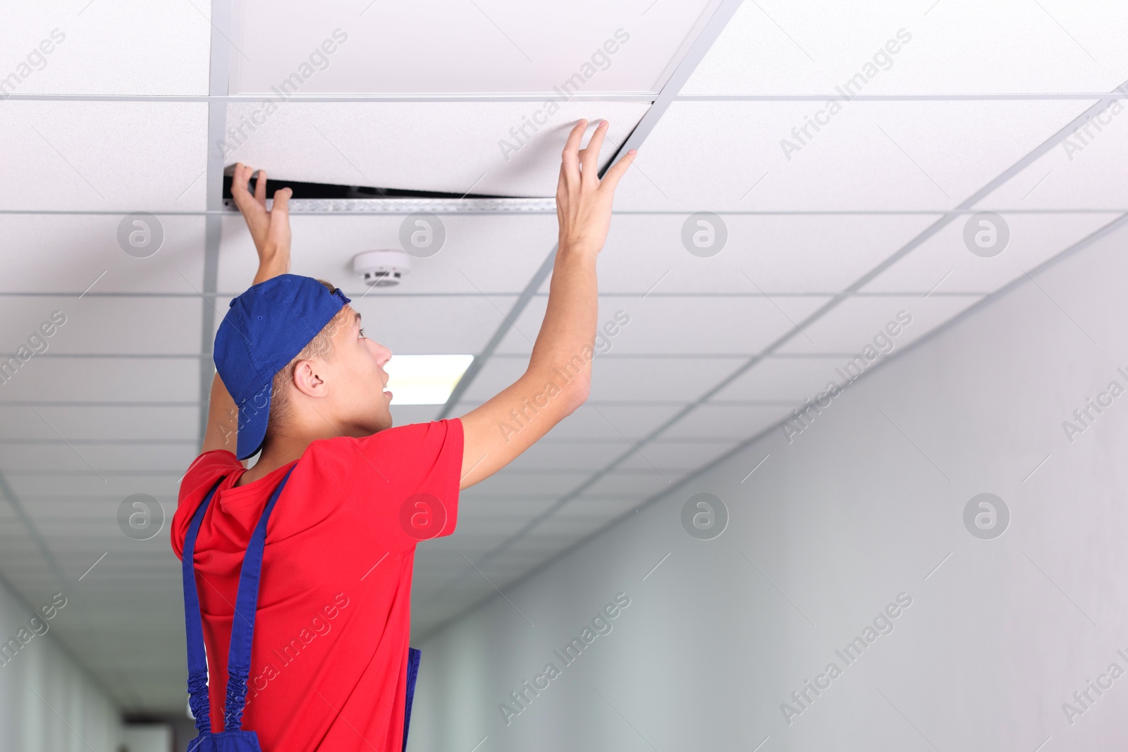 Photo of Suspended ceiling installation. Builder working with PVC tile indoors