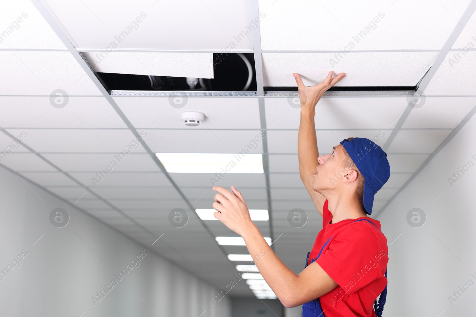 Photo of Suspended ceiling installation. Builder working with PVC tile indoors