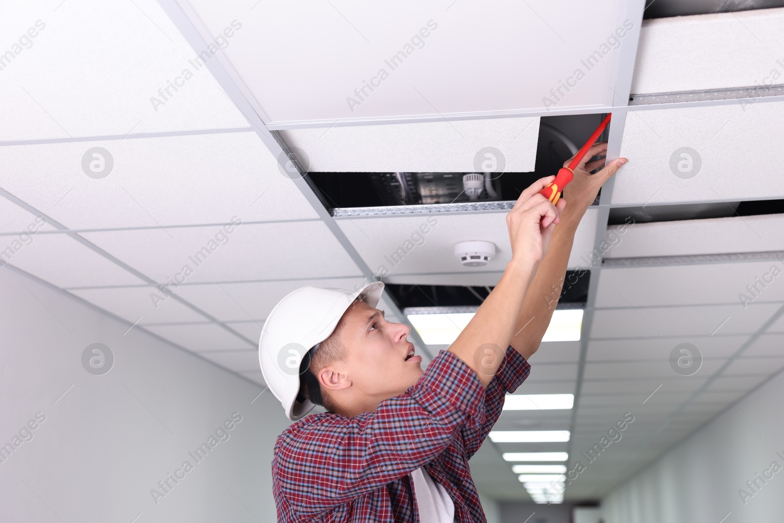 Photo of Suspended ceiling installation. Builder working with PVC tile indoors