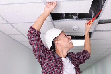 Photo of Suspended ceiling installation. Builder working with PVC tile indoors