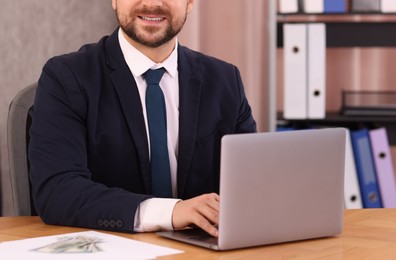 Photo of Banker working with laptop at wooden table in office