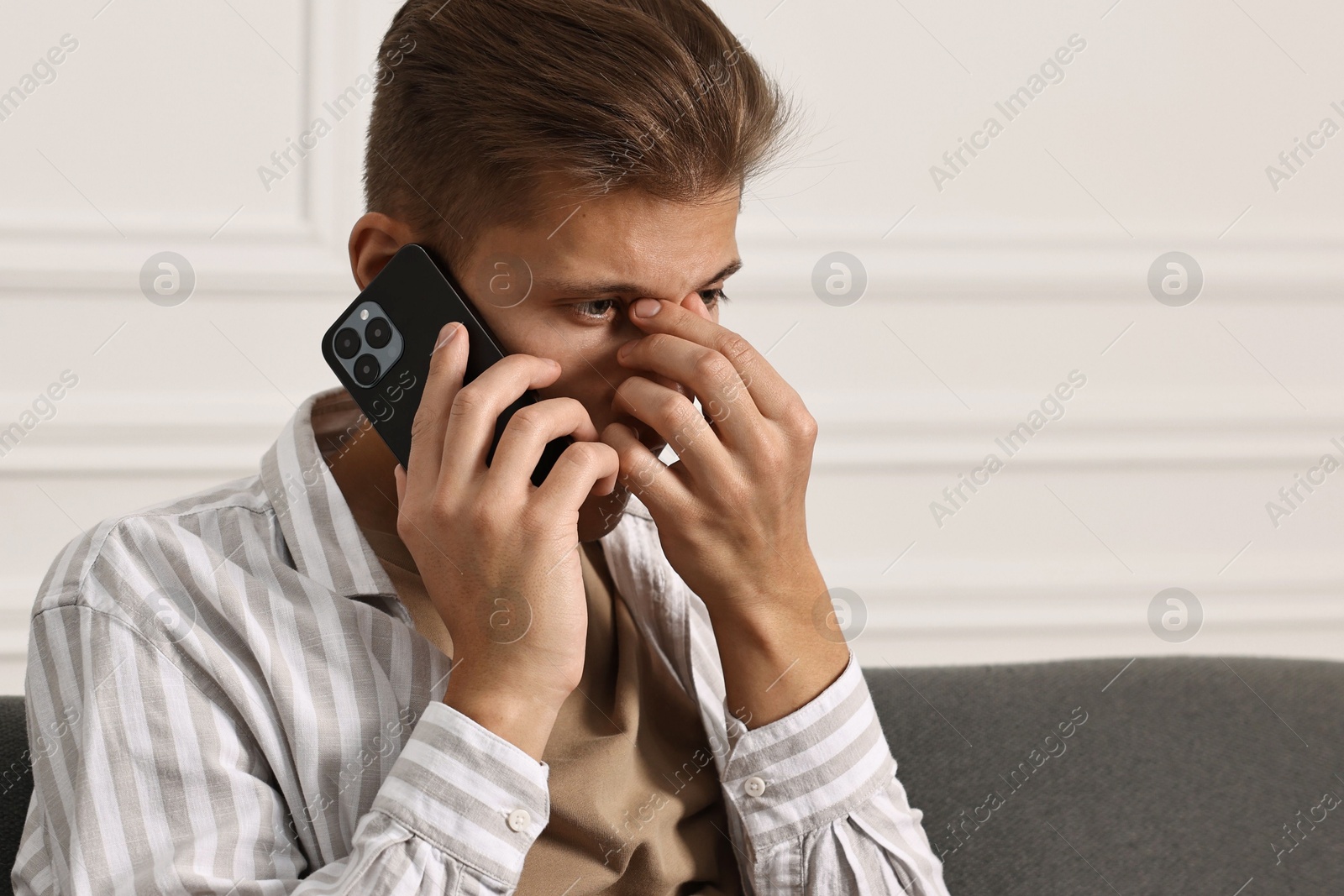 Photo of Worried man calling hotline for mental health help at home