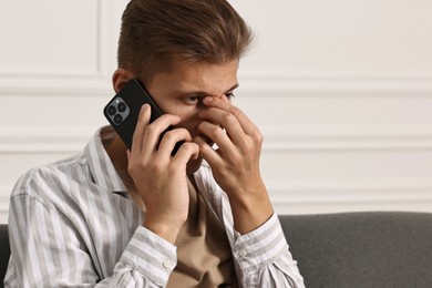 Photo of Worried man calling hotline for mental health help at home