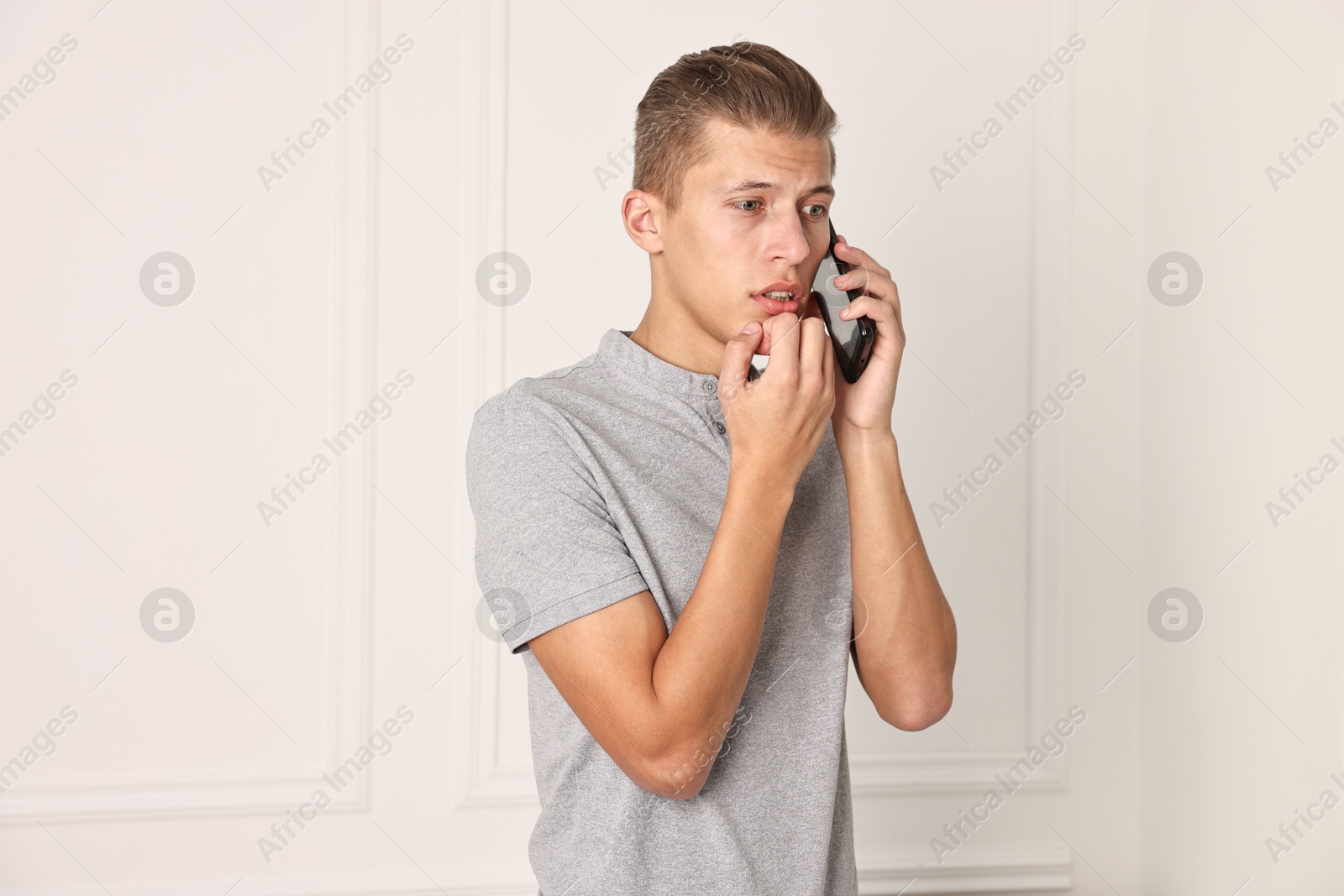 Photo of Stressed man calling hotline for mental health help indoors