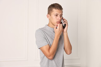 Photo of Stressed man calling hotline for mental health help indoors