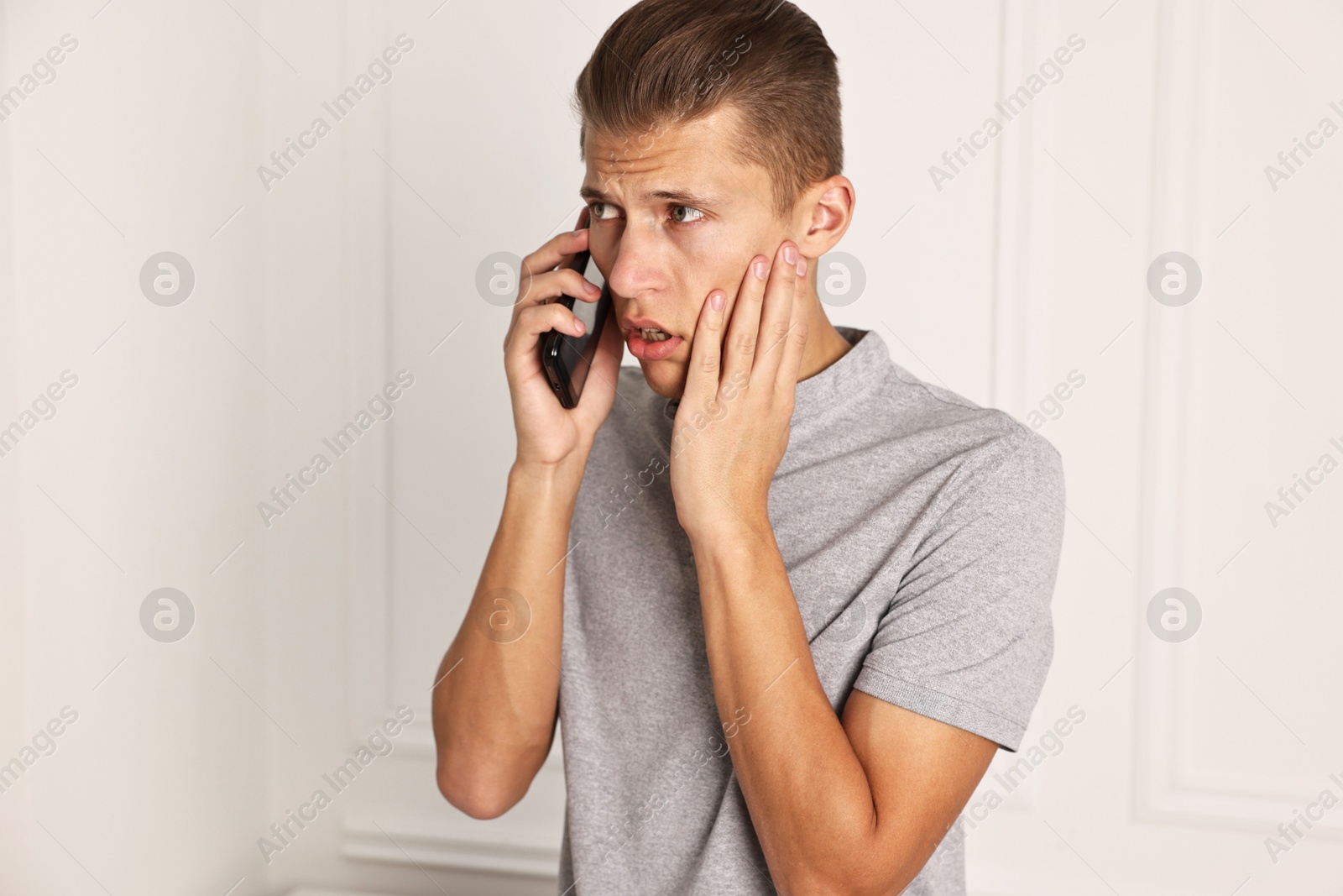 Photo of Stressed man calling hotline for mental health help indoors