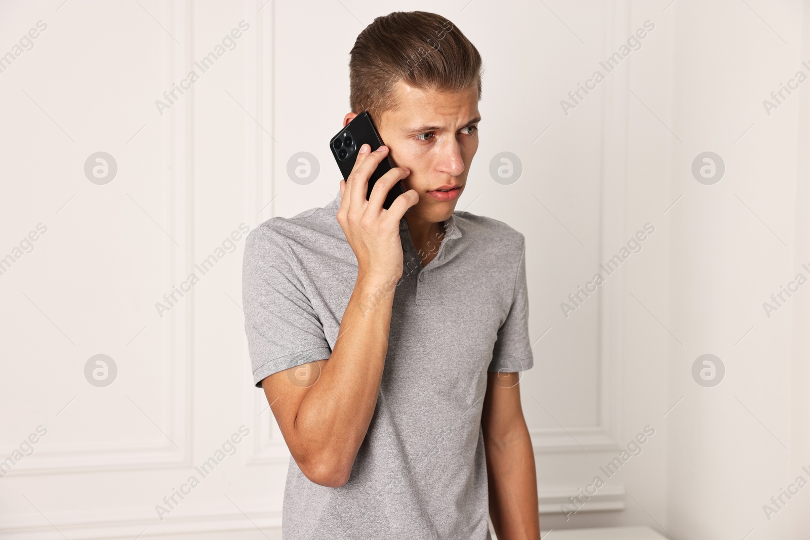 Photo of Frustrated man calling hotline for mental health help indoors