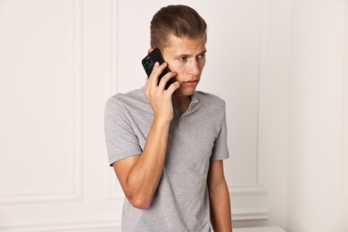 Photo of Frustrated man calling hotline for mental health help indoors