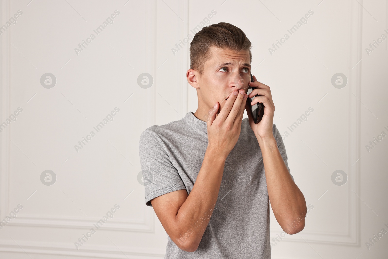 Photo of Worried man calling hotline for mental health help indoors. Space for text