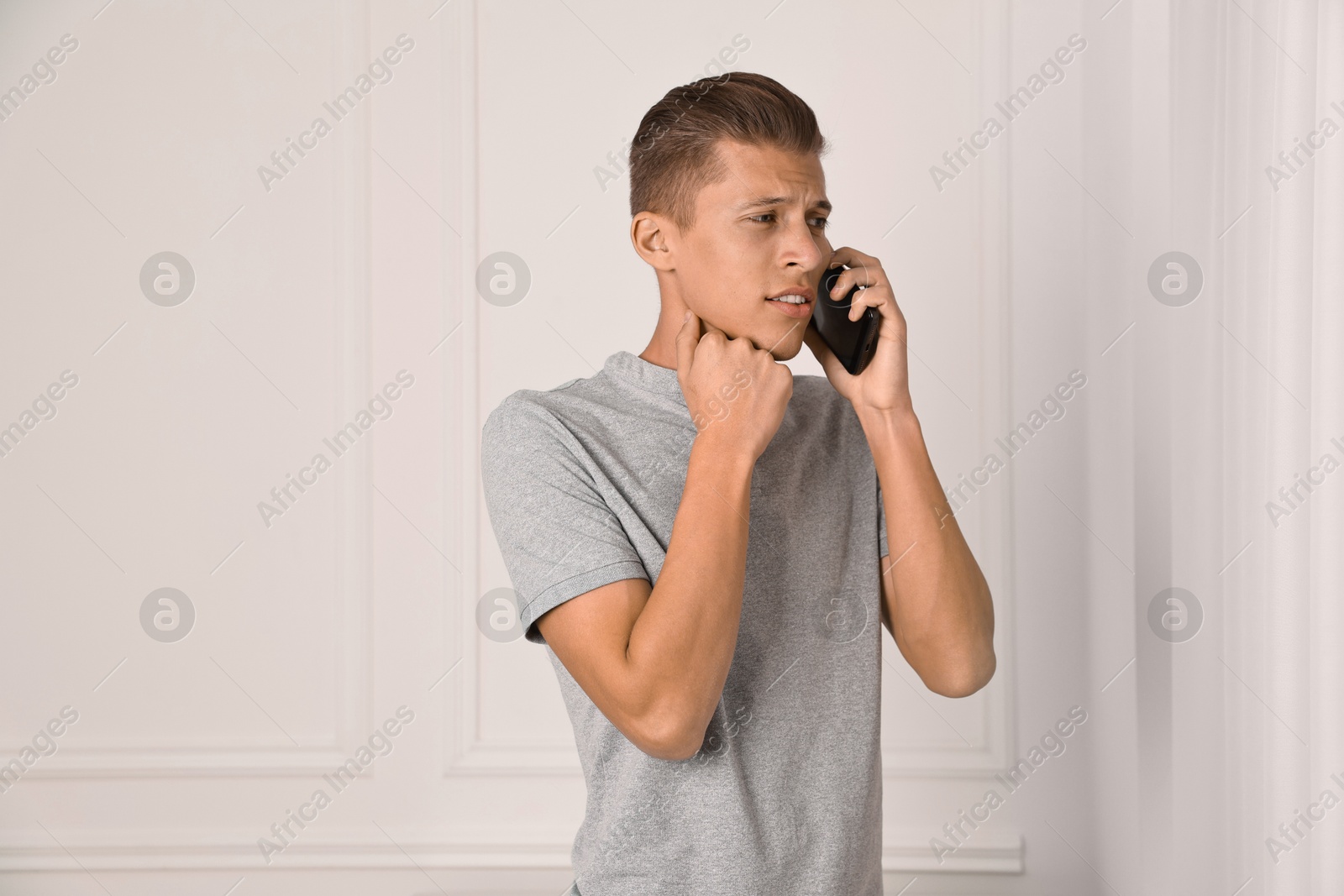 Photo of Worried man calling hotline for mental health help indoors. Space for text