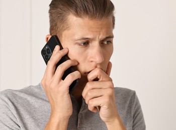 Photo of Stressed man calling hotline for mental health help indoors