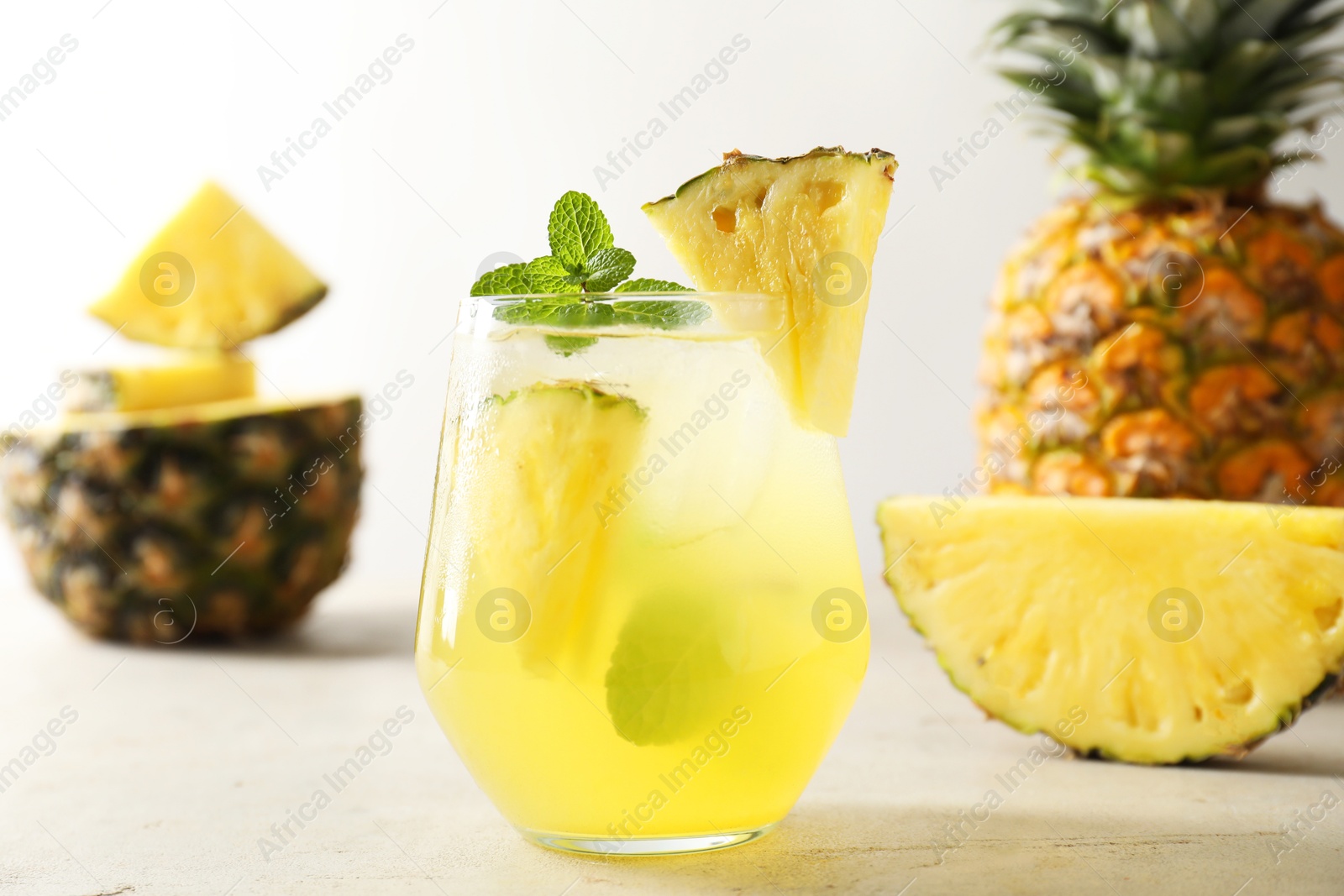 Photo of Tasty pineapple cocktail with mint in glass on light table, closeup