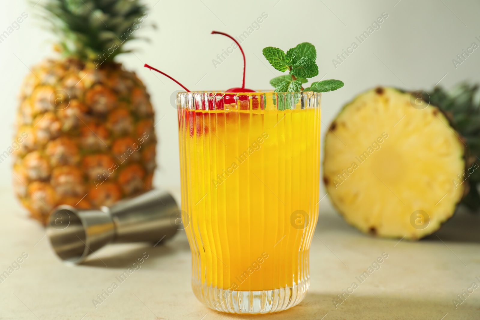 Photo of Tasty pineapple cocktail with mint and cherry in glass served on light table, closeup