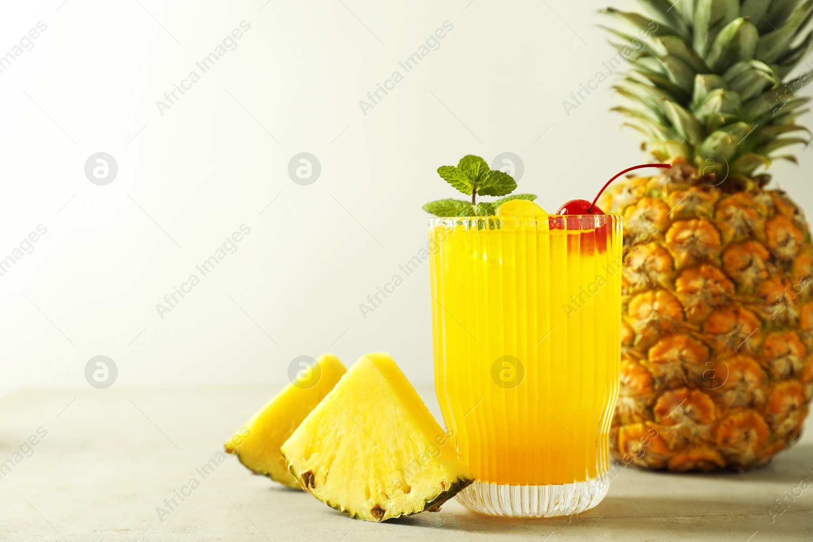 Photo of Tasty pineapple cocktail with mint and cherry in glass served on light table, space for text