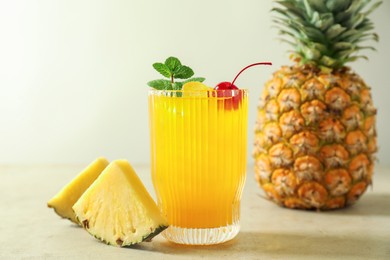 Photo of Tasty pineapple cocktail with mint and cherry in glass served on light table