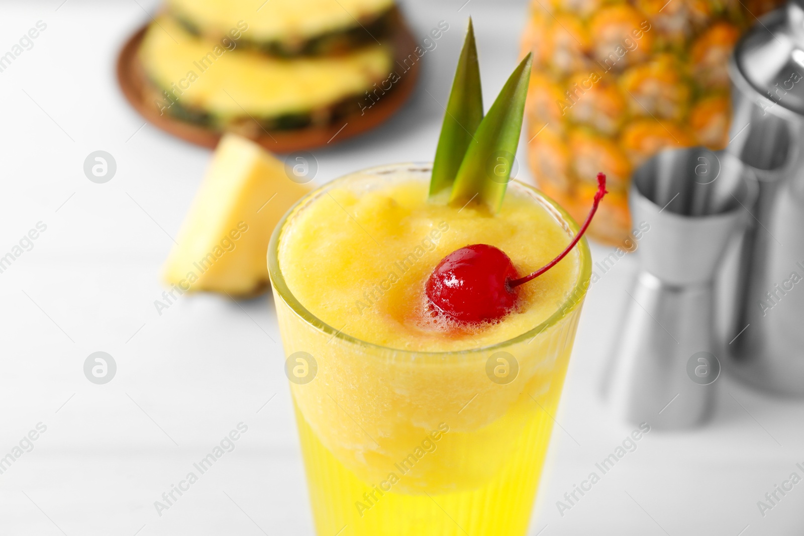 Photo of Tasty pineapple cocktail with cherry in glass on light table, closeup