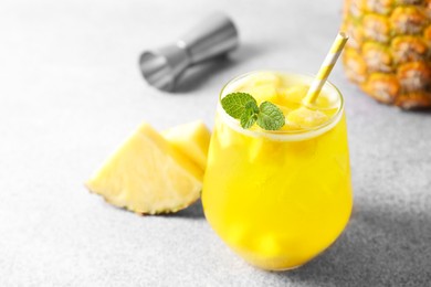 Photo of Tasty pineapple cocktail with mint in glass on gray table, closeup