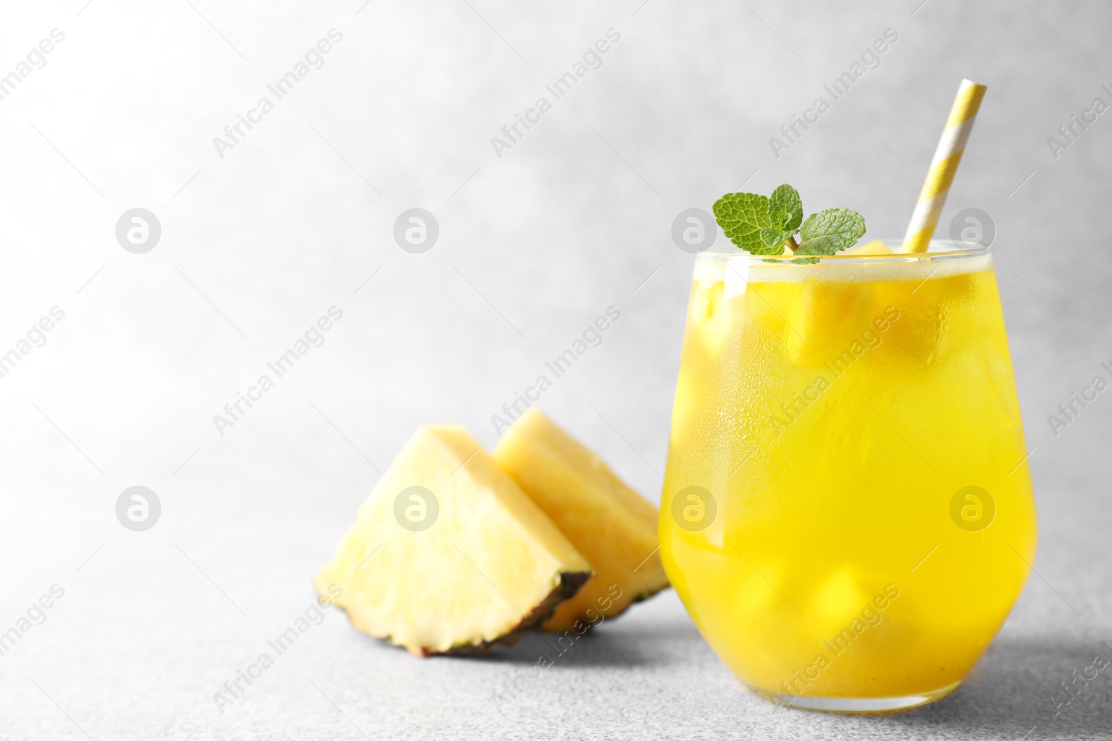 Photo of Tasty pineapple cocktail with mint in glass on gray table, space for text