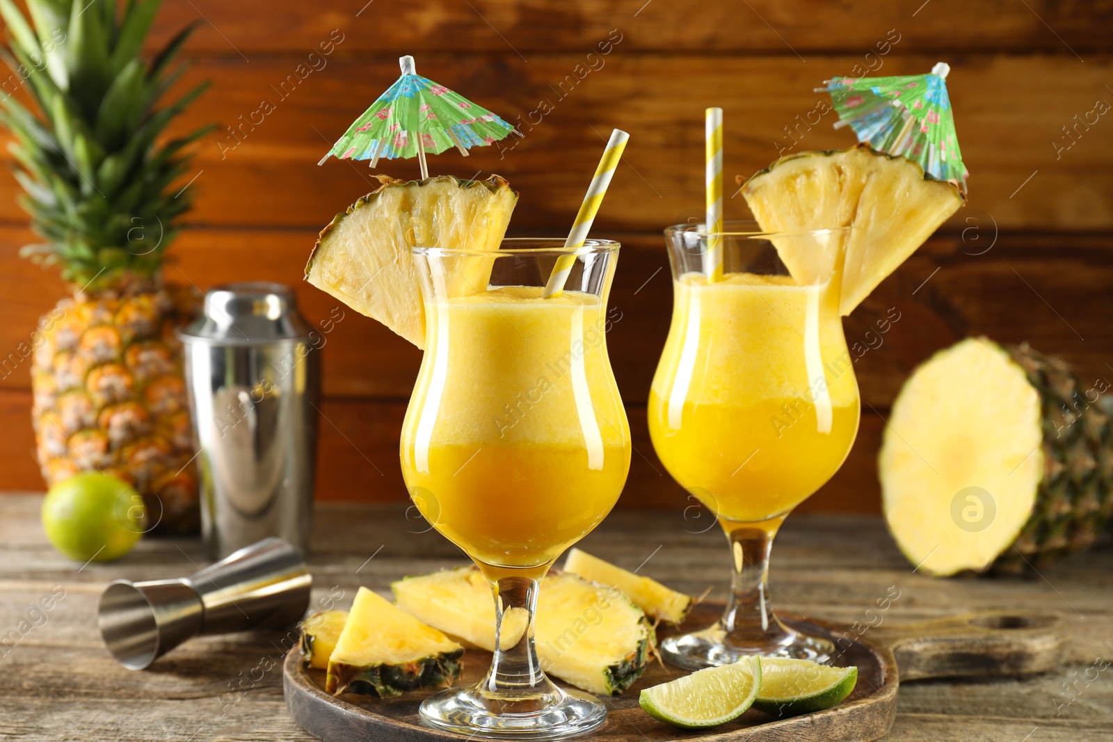 Photo of Tasty pineapple cocktail in glasses served on wooden table