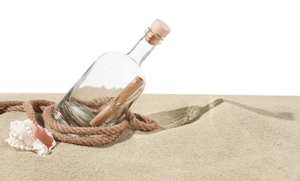 Photo of Rolled letter in corked glass bottle, rope and shell on sand against white background