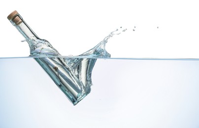 Photo of Corked glass bottle with rolled letter in water on white background