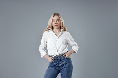 Photo of Beautiful young woman in stylish jeans on grey background