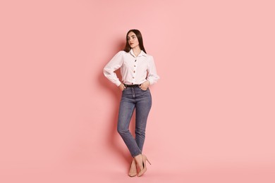 Photo of Beautiful young woman in stylish jeans on pink background