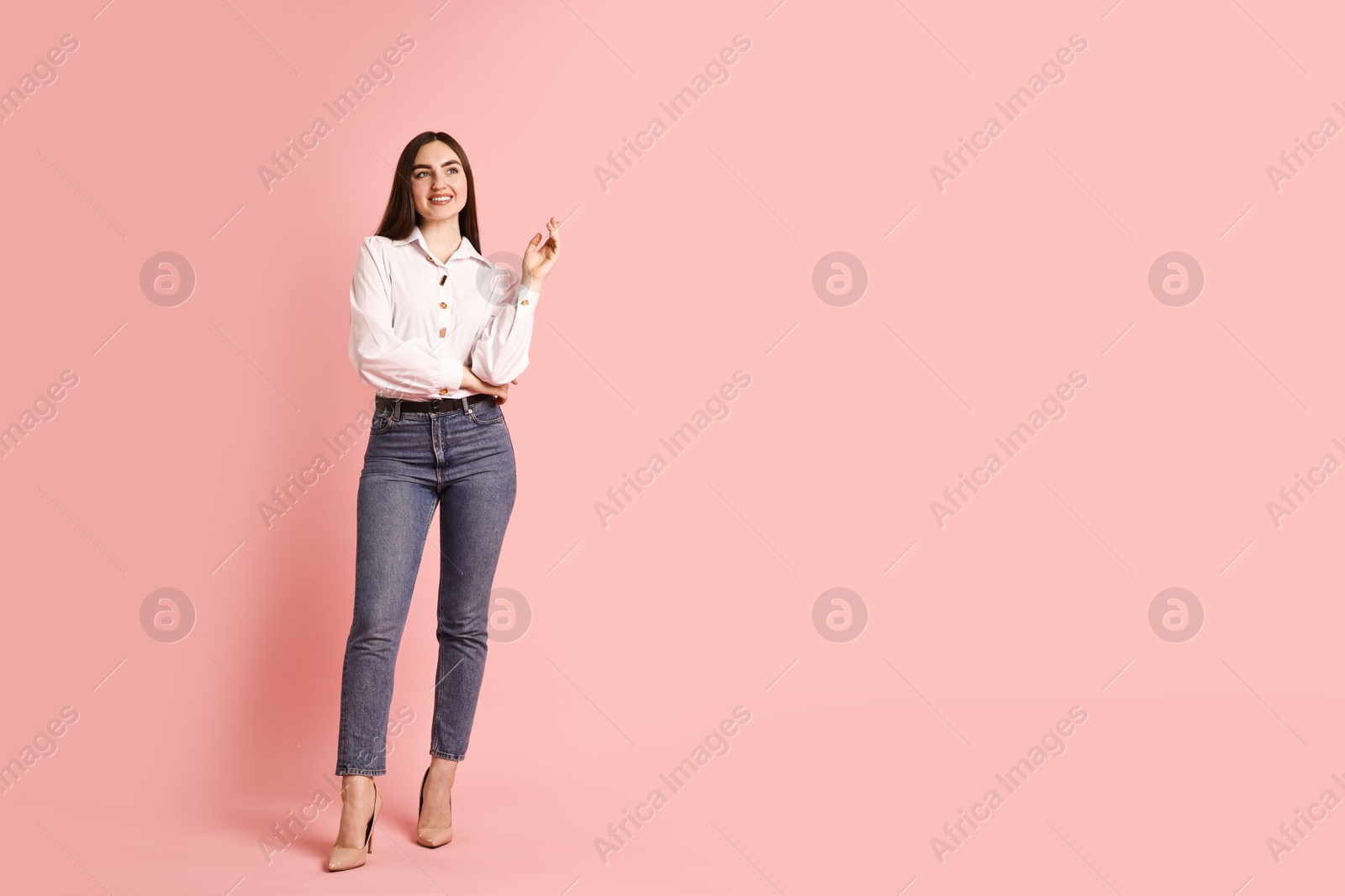 Photo of Smiling woman in stylish jeans on pink background. Space for text