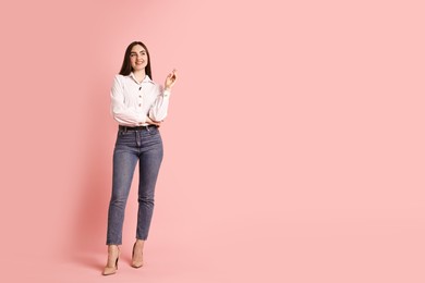 Photo of Smiling woman in stylish jeans on pink background. Space for text