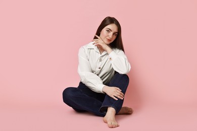 Photo of Beautiful young woman in stylish jeans on pink background