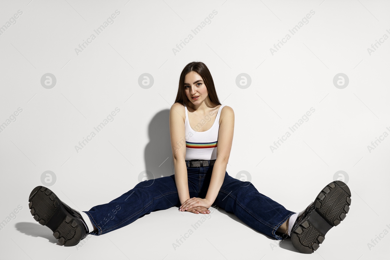 Photo of Beautiful young woman in stylish jeans posing on light background