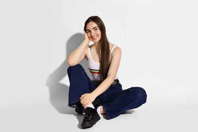 Photo of Smiling woman in stylish jeans on light background