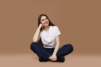 Photo of Smiling woman in stylish jeans on brown background