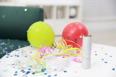 Photo of Confetti popper, serpentine streamers and other party decor on white table indoors