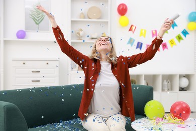 Photo of Happy woman with party popper and confetti in festive decorated room