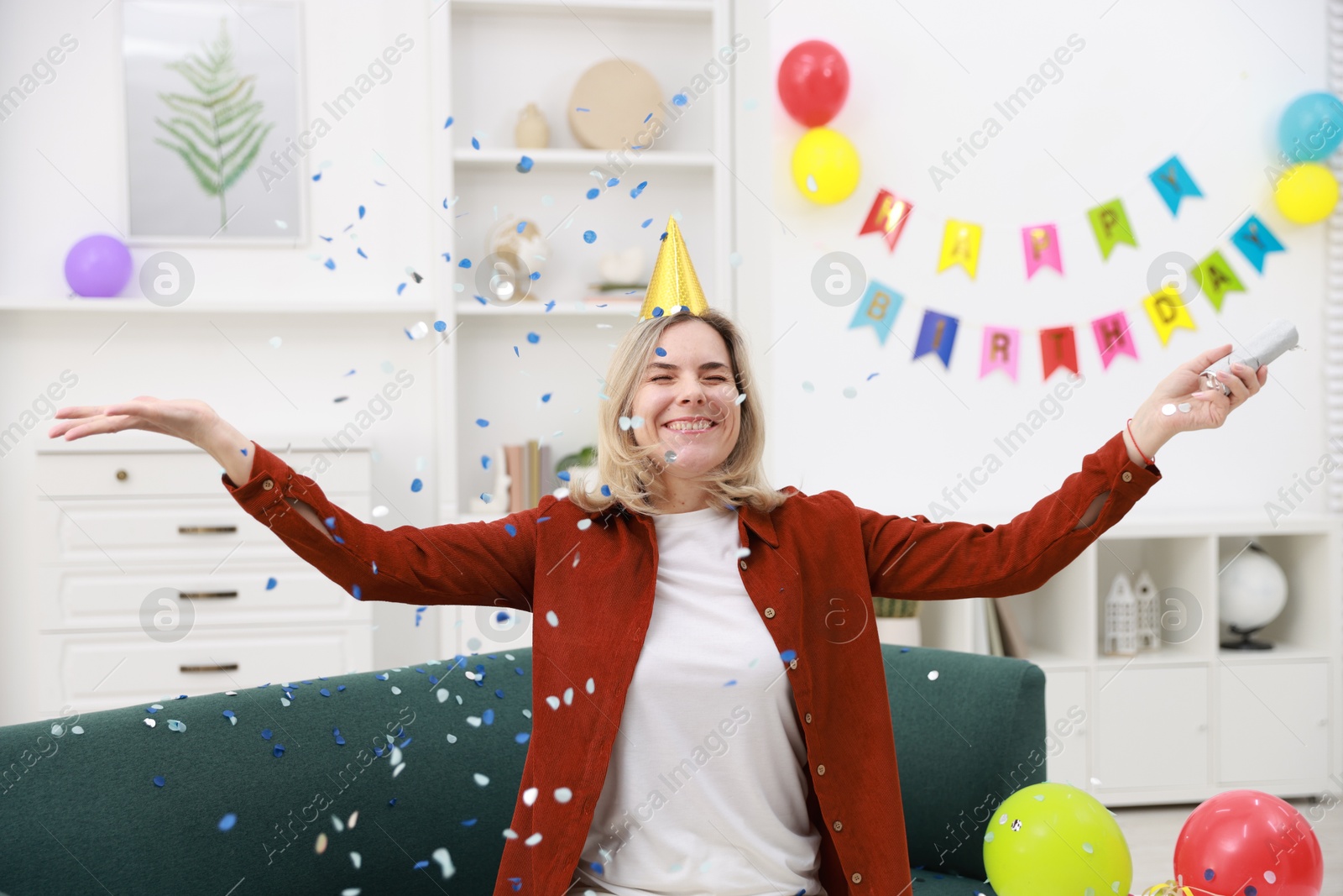 Photo of Happy woman with party popper and confetti in festive decorated room